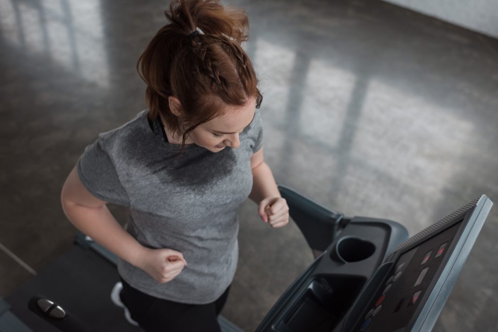 A person running on a treadmill, adjusting the speed for a challenging cardio workout